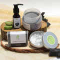 Collection of natural skincare products including a bottle, jar, and soap on a wooden tray.