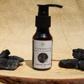 Bottle of P.S. Products Charcoal Face Wash on a wooden surface with charcoal blocks.