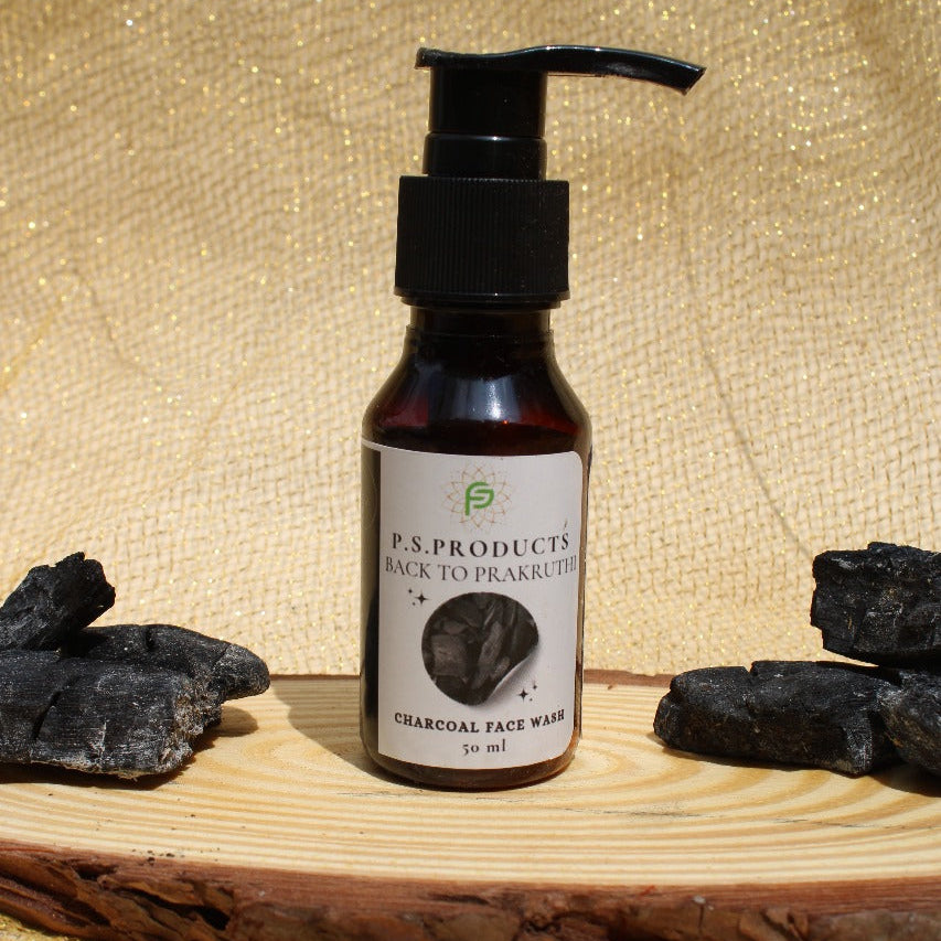 Bottle of P.S. Products Charcoal Face Wash on a wooden surface with charcoal blocks.