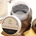 Jar of charcoal face pack with a label on a textured surface