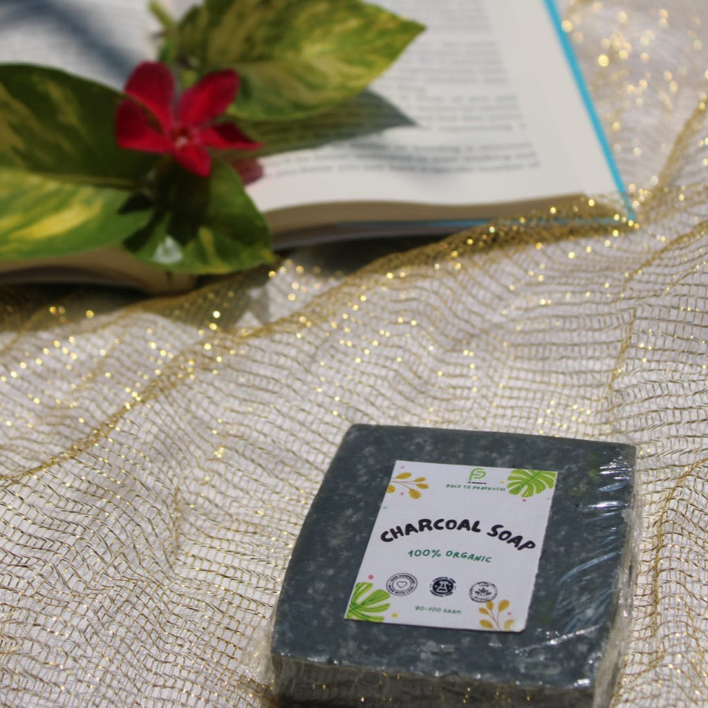 Bar of charcoal soap with a label on a decorative surface with a book and flowers in the background