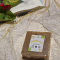 Bar of soap with a label on a textured surface with a plant in the background