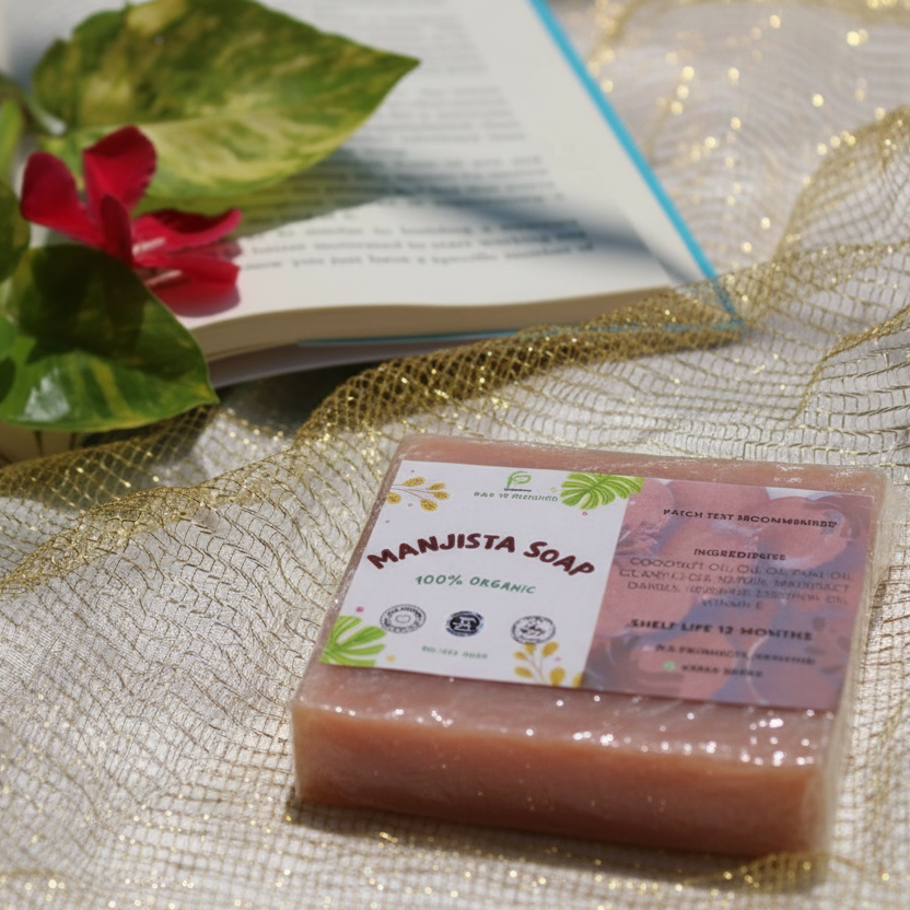Manjista Soap bar with packaging on a decorative surface with a book and flowers.